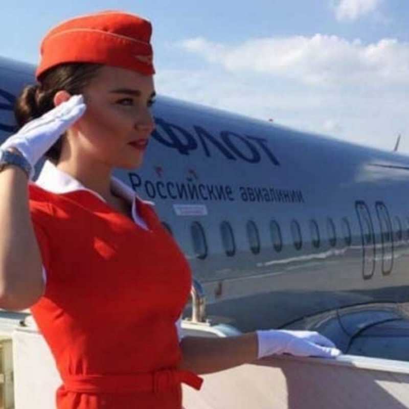Открытка стюардесса в красном отдает честь чудесного полета Щасливої ​​дороги 